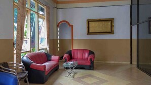 Une pièce avec deux canapés en cuir rouge, une table basse en verre et un fauteuil bleu.