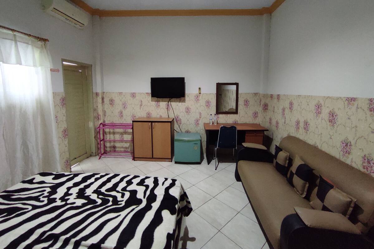 A room with a bed, a sofa, a desk, a TV, and a mirror.