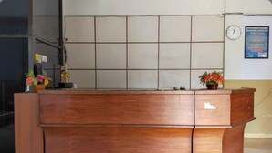 Un comptoir d’accueil avec un mur recouvert de carreaux derrière, une horloge et une affiche accrochée au mur.