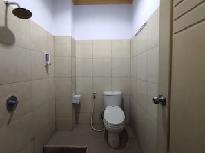 Ein kleines Badezimmer mit gefliesten Wänden, einer Toilette, einer Dusche und einem Händetrockner.