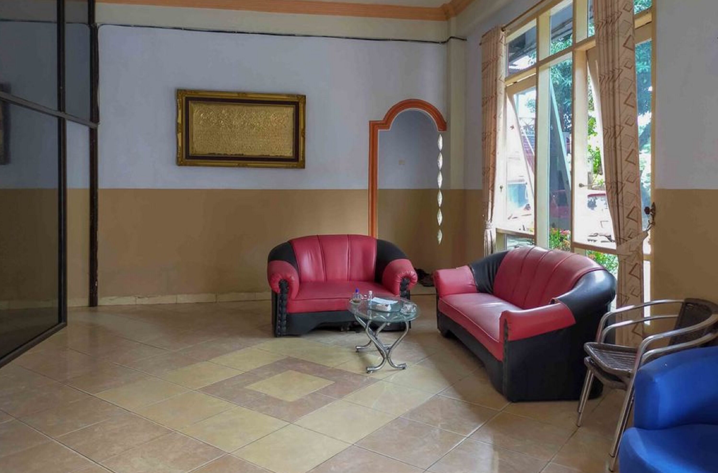 A room with two red leather sofas, a glass coffee table, and a blue chair.