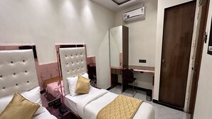 A hotel room with two beds, a desk, a chair, a wardrobe, and an air conditioning unit. - Hotel Orchid Inn - Andheri (Mumbai)