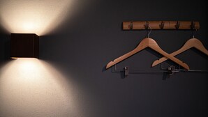 Un porte-manteaux en bois fixé au mur, avec deux cintres, le tout placé devant un mur à texture.