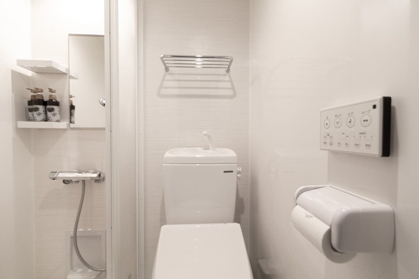 A modern bathroom with a toilet, a shower, and a toilet paper holder.