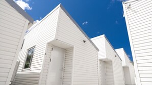 Une rangée de bâtiments blancs, à un seul étage, sous un ciel d’un bleu limpide.