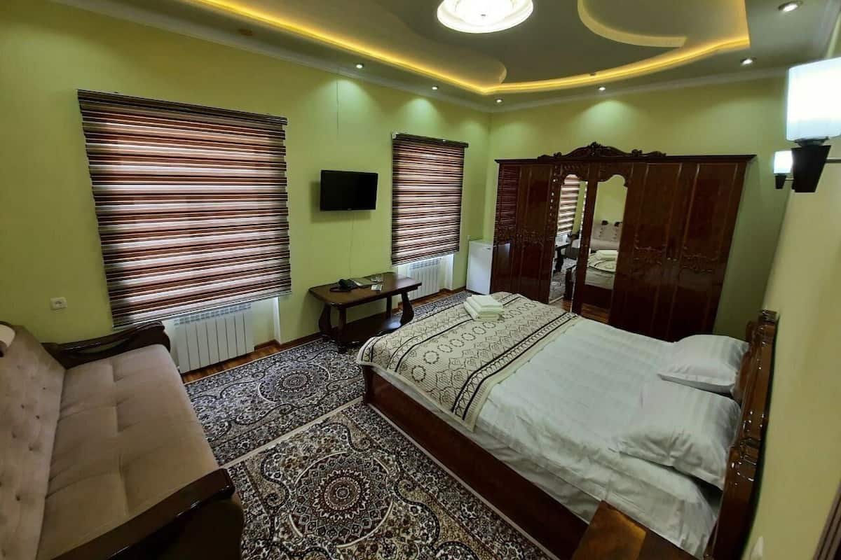 A bedroom with a large bed, a sofa, a TV, and a wardrobe.