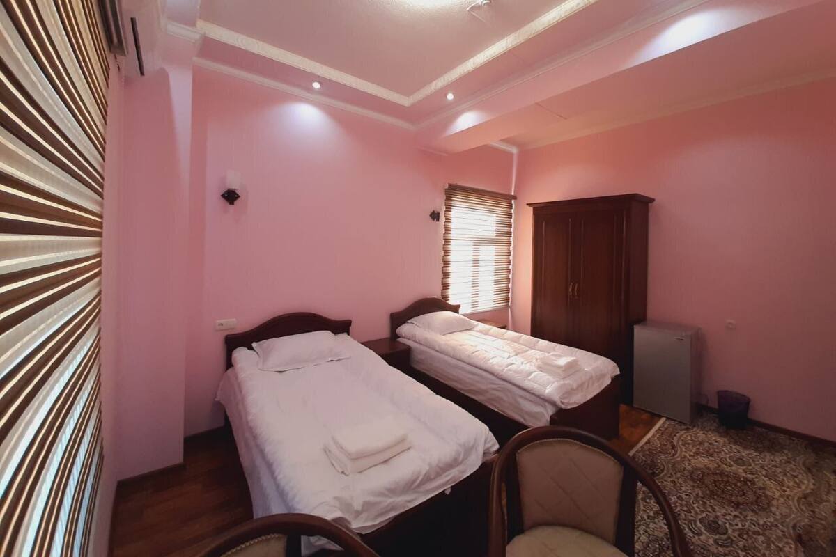 A bedroom with two beds, a wardrobe, a small table, and a radiator.