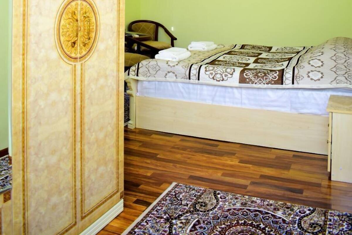 A bedroom with a bed, a wardrobe, a television, and a patterned rug.