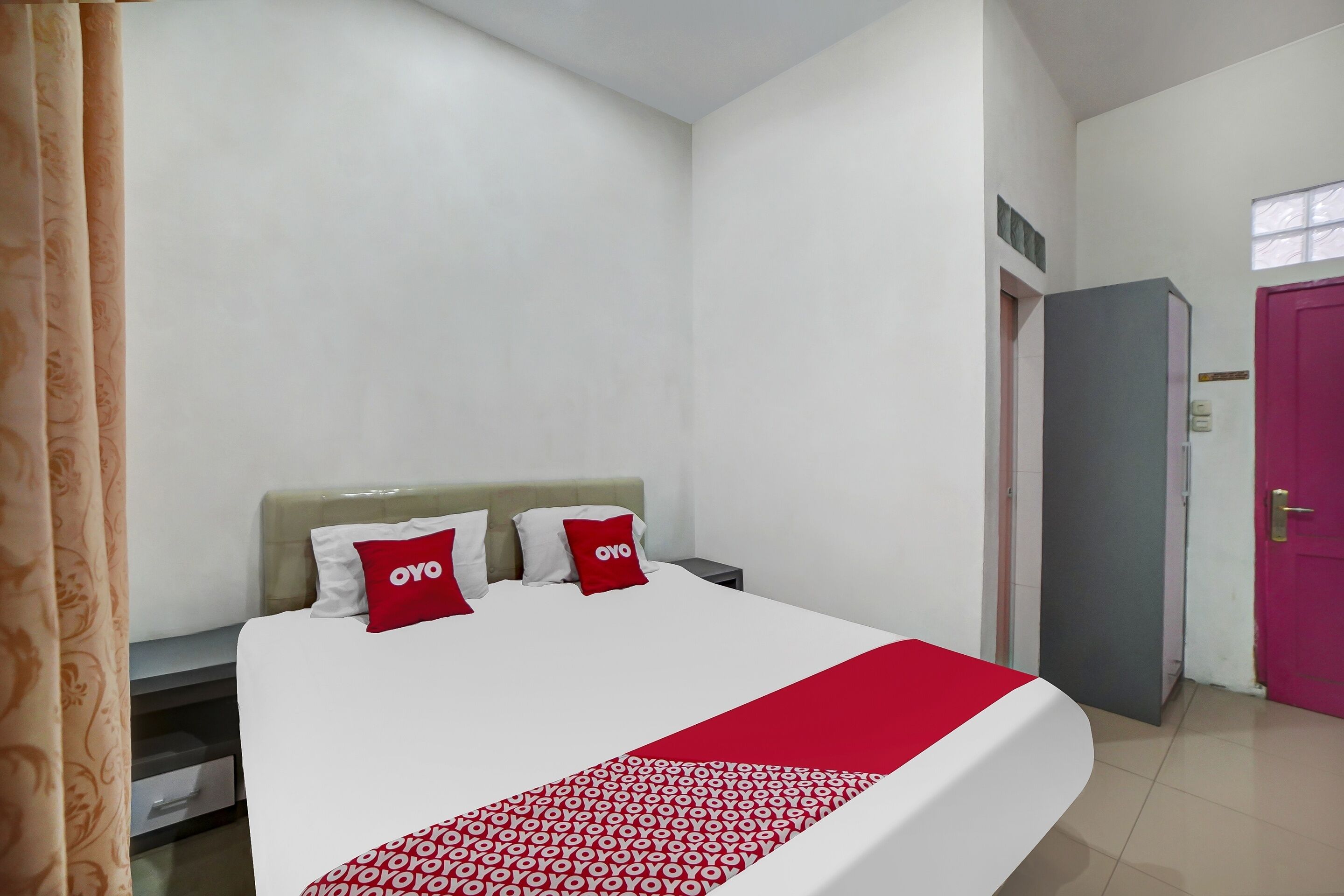 A hotel room with a bed, a nightstand, a wardrobe, and a door.