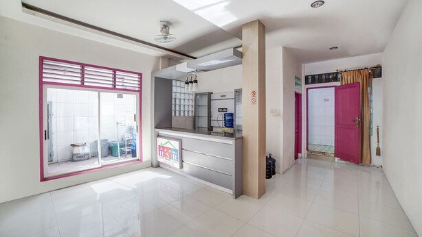 A hotel reception area with a glass door entrance, a reception desk, and a visible bathroom sign. - Hotel O Asri Residence (Medan)