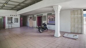 A spacious indoor area with a tiled floor, a motorcycle, and a sign for ASRI Residence. - Hotel O Asri Residence (Medan)
