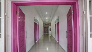 A hallway with pink doors and a sign for ASRI. - Hotel O Asri Residence (Medan)