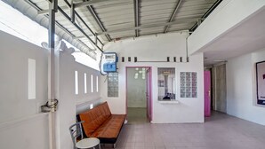 A spacious indoor area with a high ceiling, a bench, a chair, and a door leading to another room. - Hotel O Asri Residence (Medan)