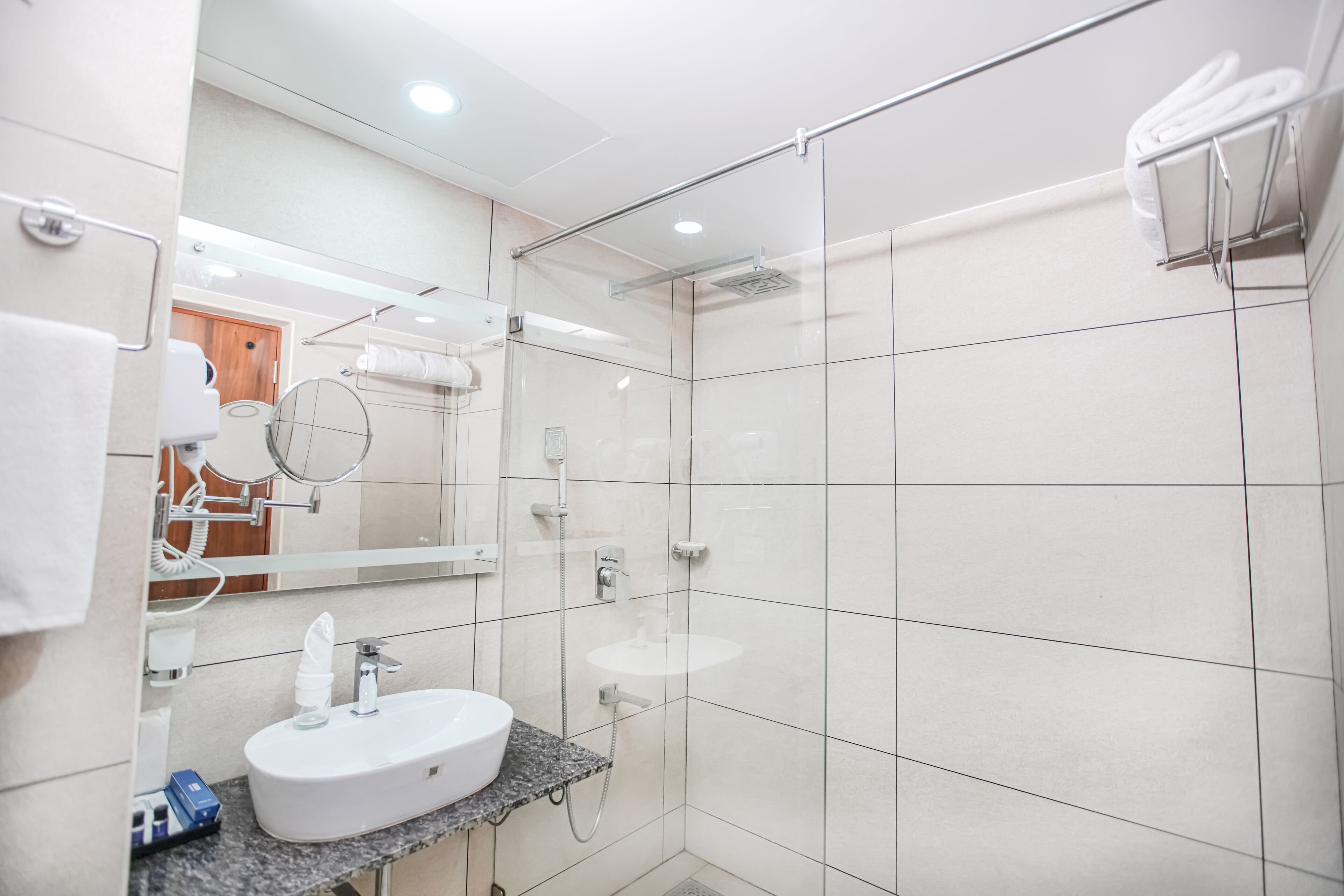 A modern bathroom with a white sink, a glass shower enclosure, and a towel rack.