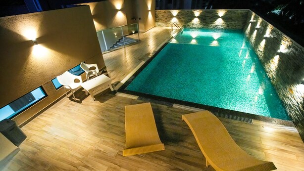 A swimming pool with lounge chairs and a staircase leading to an upper level. - Kkm International (Thiruvananthapuram)