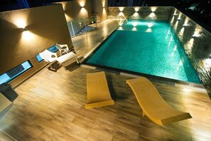 En pool med solstolar och en trappa som leder upp till en övre våning.