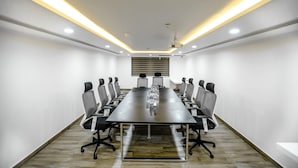A conference room with a long table, chairs, a projector, and a whiteboard. - Kkm International (Thiruvananthapuram)