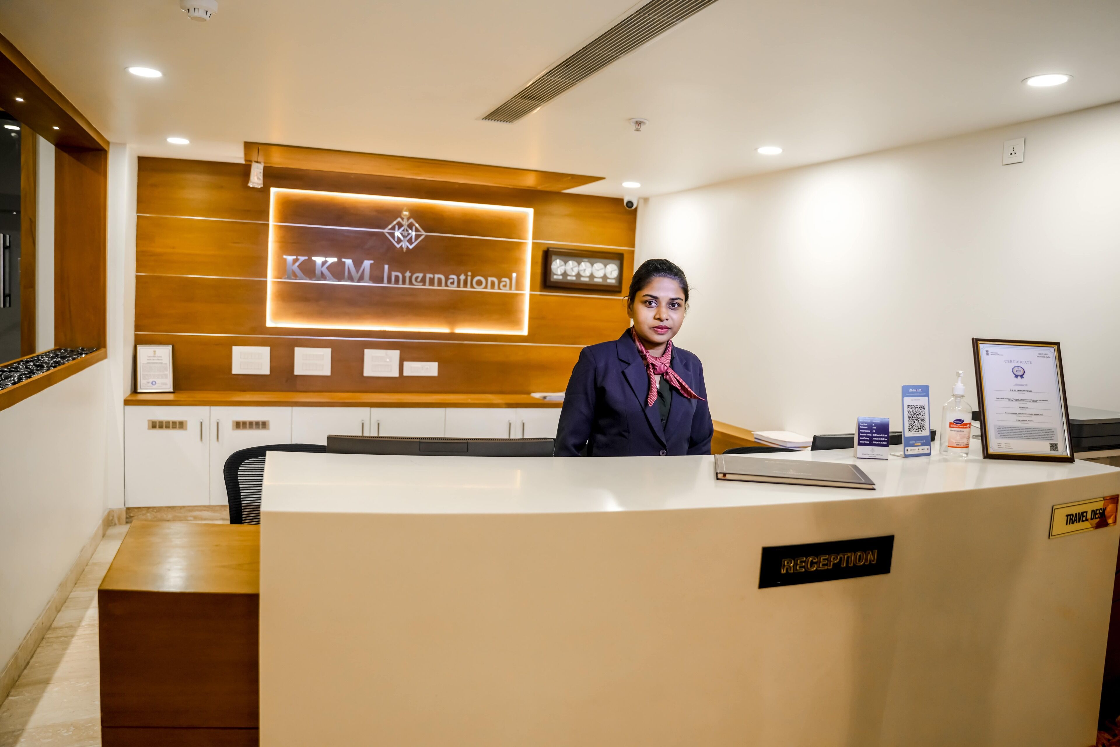 A reception desk with a sign reading "KKM International" and a "Reception" sign on the desk.