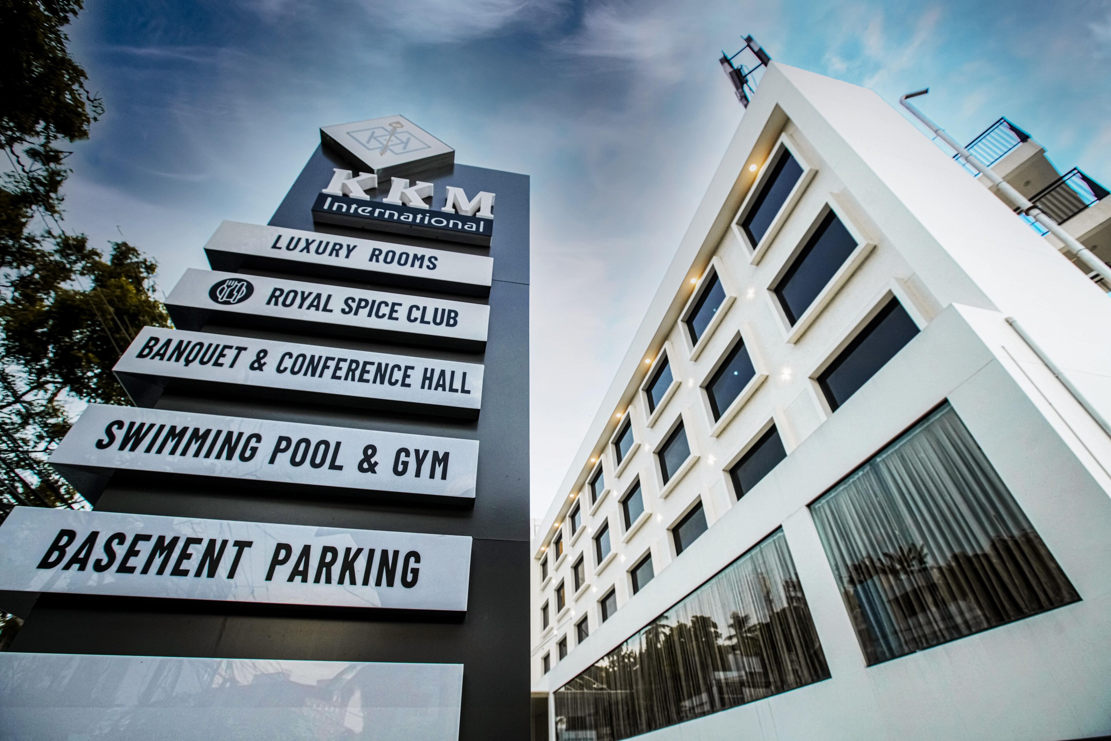Une pancarte indique les équipements disponibles, notamment des chambres de luxe, un club royal dédié aux épices, une salle de banquet et de conférence, une piscine et une salle de sport, ainsi qu’un parking souterrain.