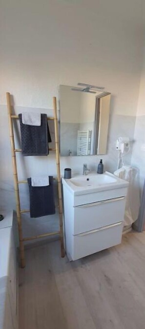 Bathroom features a white vanity, sink, and toilet, along with a towel rack and wooden ladder.