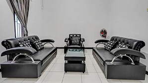A modern living room with a sofa set, a coffee table, and a fan. - OYO 91334 Permata Papua Guest House (Pameungpeuk)