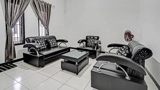 A modern living room with black leather sofas, a glass coffee table, and a black armchair. - OYO 91334 Permata Papua Guest House (Pameungpeuk)