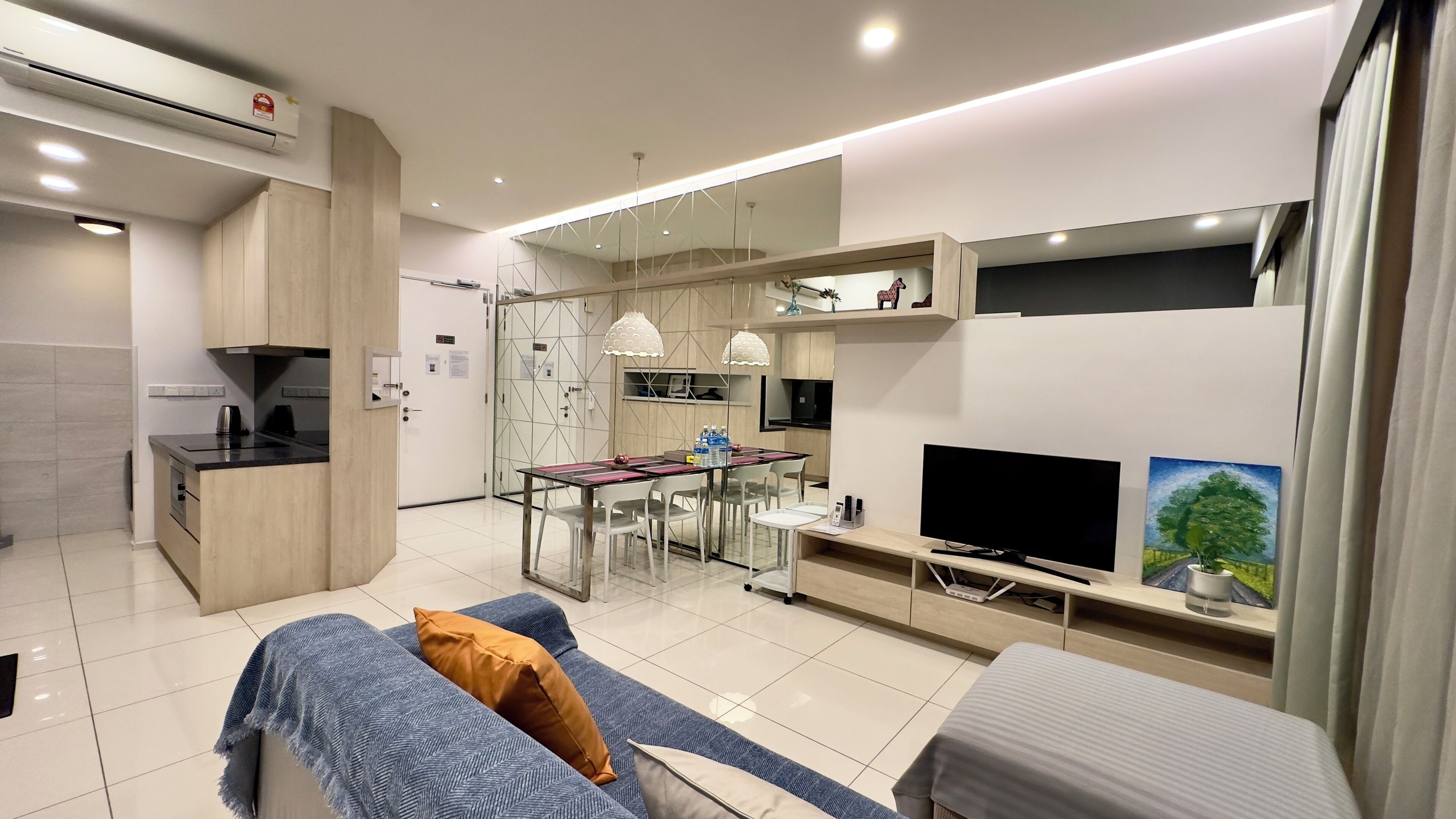 A modern living room with a sofa, a TV, and a dining area with chairs and a table.