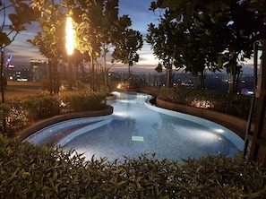 A swimming pool surrounded by greenery, with a cityscape in the background. - The Robertson Residence (Kuala Lumpur)