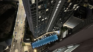 A high-rise building with multiple floors, a parking lot with cars, and a blue water feature in the foreground. - The Robertson Residence (Kuala Lumpur)