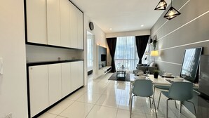 A modern kitchen with white cabinets, a dining area with a table and chairs, and a living area with a sofa and a TV. - The Robertson Residence (Kuala Lumpur)