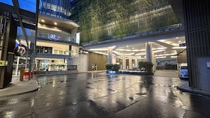 A modern building with a wet ground, large columns, and a covered entrance area. - The Robertson Residence (Kuala Lumpur)