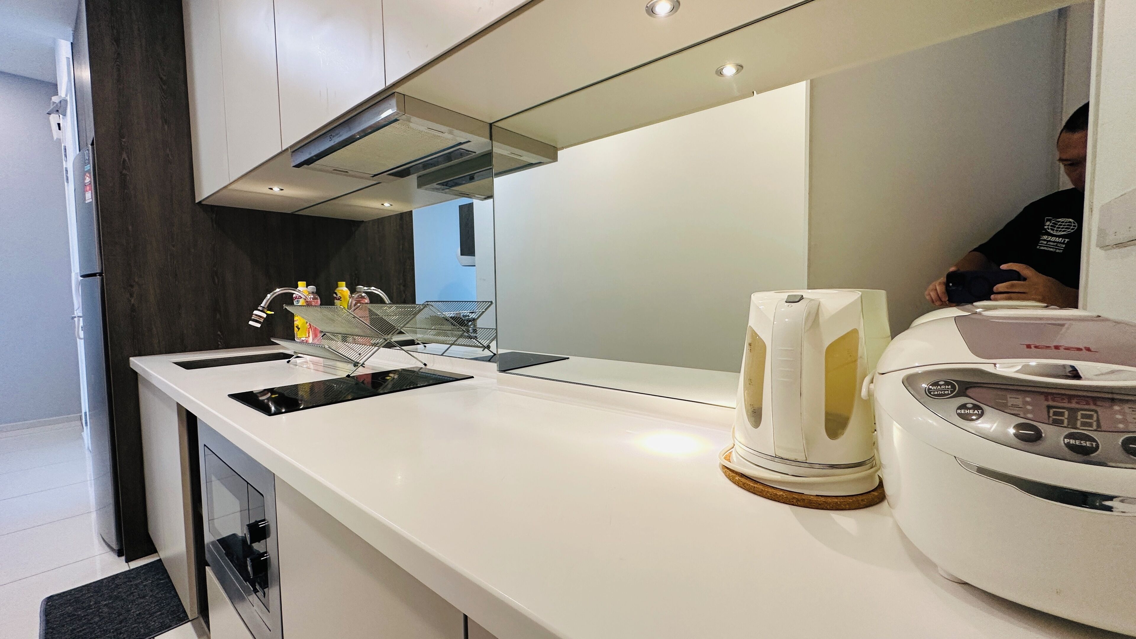 Une cuisine moderne avec un plan de travail blanc, des appareils en acier inoxydable et une machine à café.