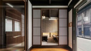 Une pièce de style japonais traditionnel, avec un sol recouvert de tatamis, des portes coulissantes et un luminaire suspendu moderne.