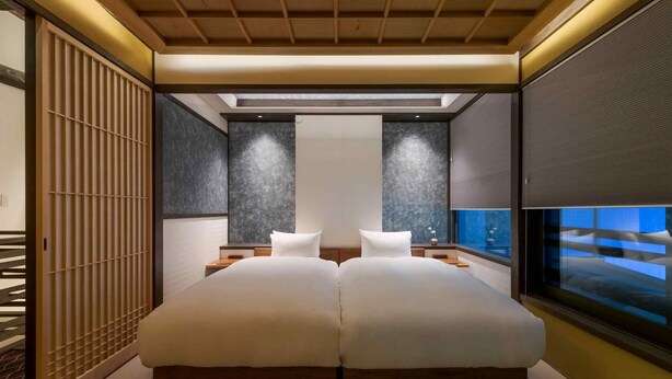 Une chambre moderne avec un grand lit, une vue sur la ville et un paravent coulissant de style japonais.