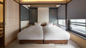 Une chambre moderne avec deux lits, une grande fenêtre et un paravent japonais traditionnel en papier.