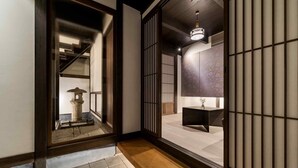 Un intérieur japonais traditionnel avec un sol recouvert de tatamis, un paravent shoji, une lanterne en pierre et un luminaire suspendu.