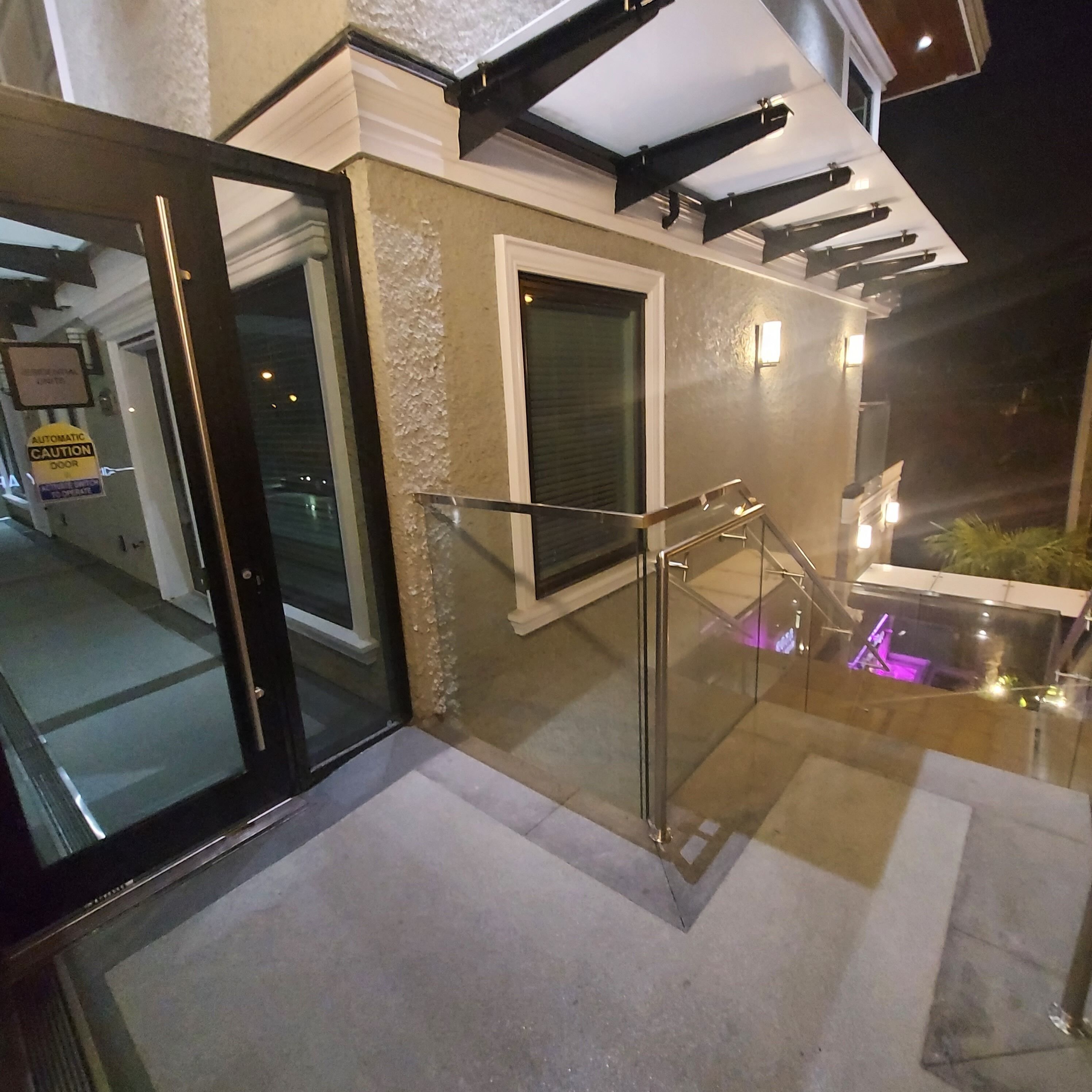Una escalera con barandillas de vidrio que lleva a un balcón con vista al cielo nocturno.