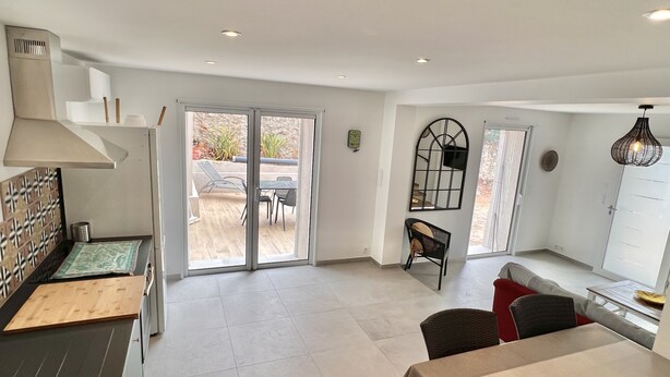 Una cocina amplia con una isla grande, puertas de vidrio corredizas que dan a un patio exterior y un comedor con mesa y sillas.