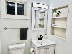 A bathroom with a toilet, sink, towel rack, mirror, and a small shelf with a potted plant. - Lovely 1 bedroom 1B1B in a cozy house (San Jose)