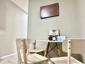 A small dining area with two wooden chairs, a white table, a framed artwork, a small potted plant, a clock, and a sign that says "WIFI". - Lovely 1 bedroom 1B1B in a cozy house (San Jose)