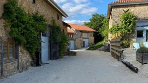 A narrow gravel path leading to stone buildings with red-tiled roofs, wooden fences, and greenery. - Holiday Home in Romefort near Lac de Vassiviere (Saint Léonard de Noblat)