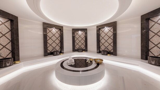 Un área de spa moderna con un jacuzzi circular, suelo de mármol y paneles decorativos en la pared.