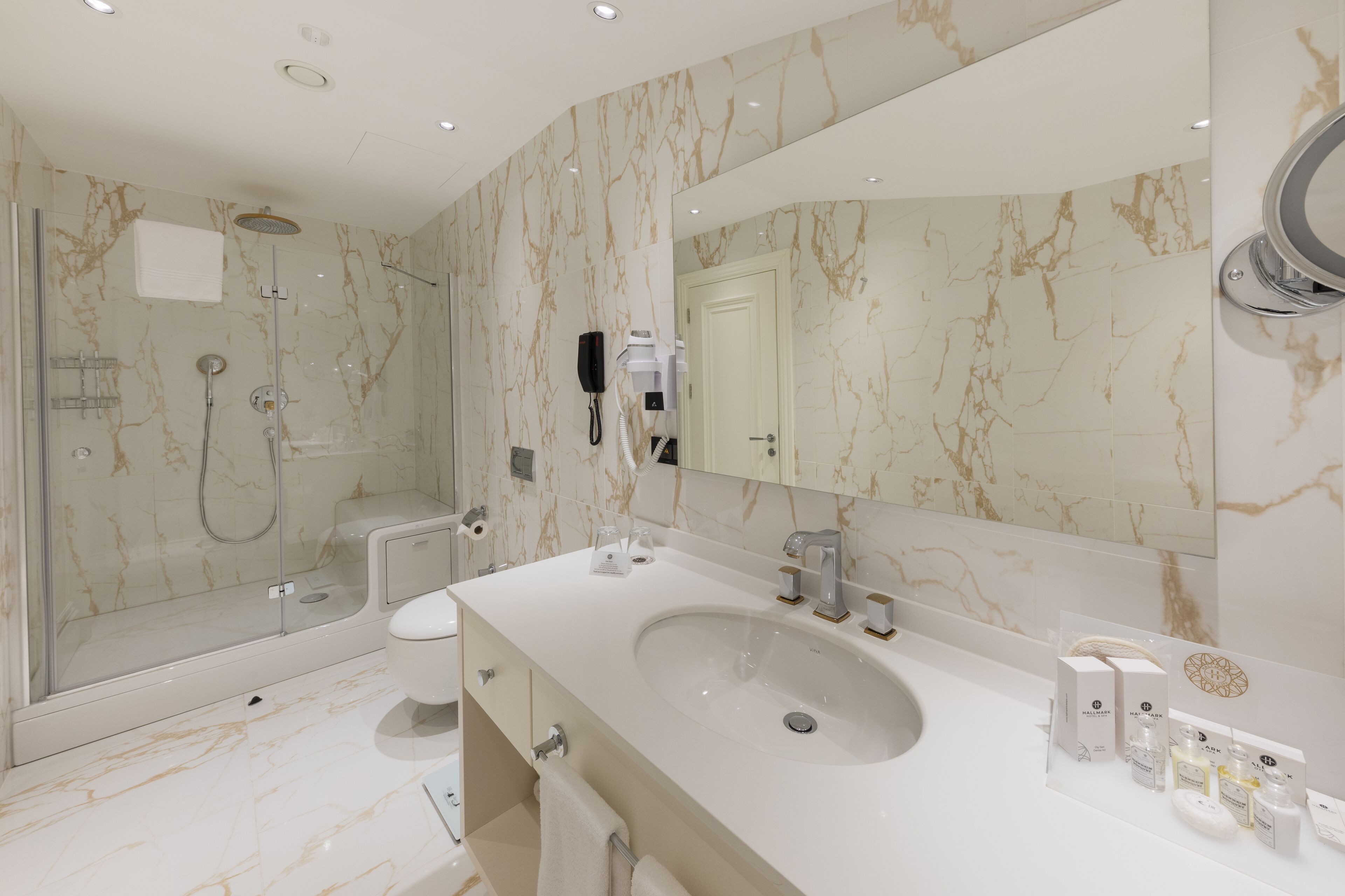 A modern bathroom with a large sink, a glass-enclosed shower, and a marble backsplash.