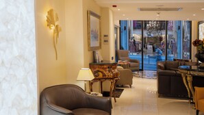 Un vestíbulo de hotel moderno con sofás de cuero, una mesa de centro de mármol y una araña.