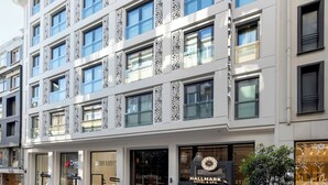 Un hotel de varios pisos con fachada moderna, amplias ventanas y una entrada destacada con un cartel.