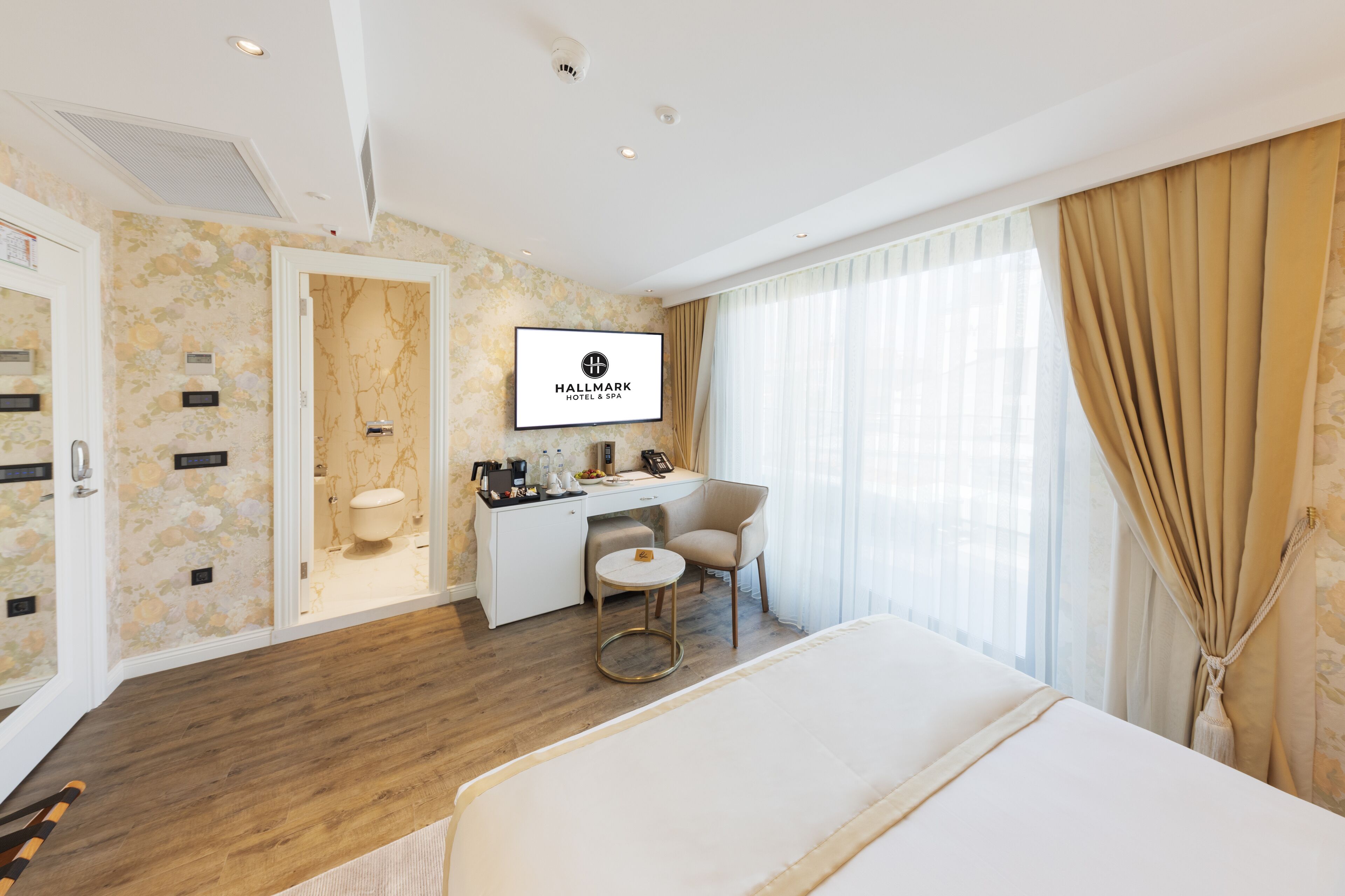 A hotel room with a bed, desk, chair, and a bathroom visible through an open door.