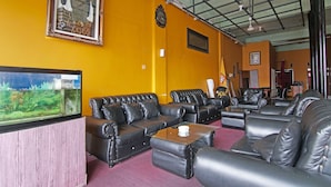 A room with black leather sofas, a wooden cabinet, a fish tank, and a ceiling with a metal grid. - SPOT ON 91761 Ramah Tamah Homestay Syariah (Pekanbaru)