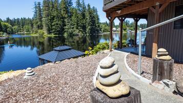 Une terrasse au bord du lac, dotée d’une rambarde en bois, d’un empilement de pierres et d’un parasol alimenté par énergie solaire.