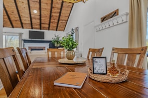 A wooden dining table with chairs, a notebook, a framed sign, and a decorative basket.