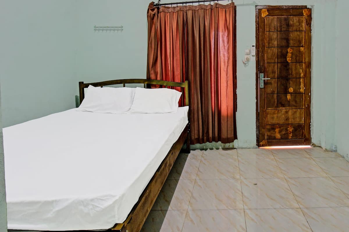 A bedroom with a single bed, a wooden door, and a curtain.